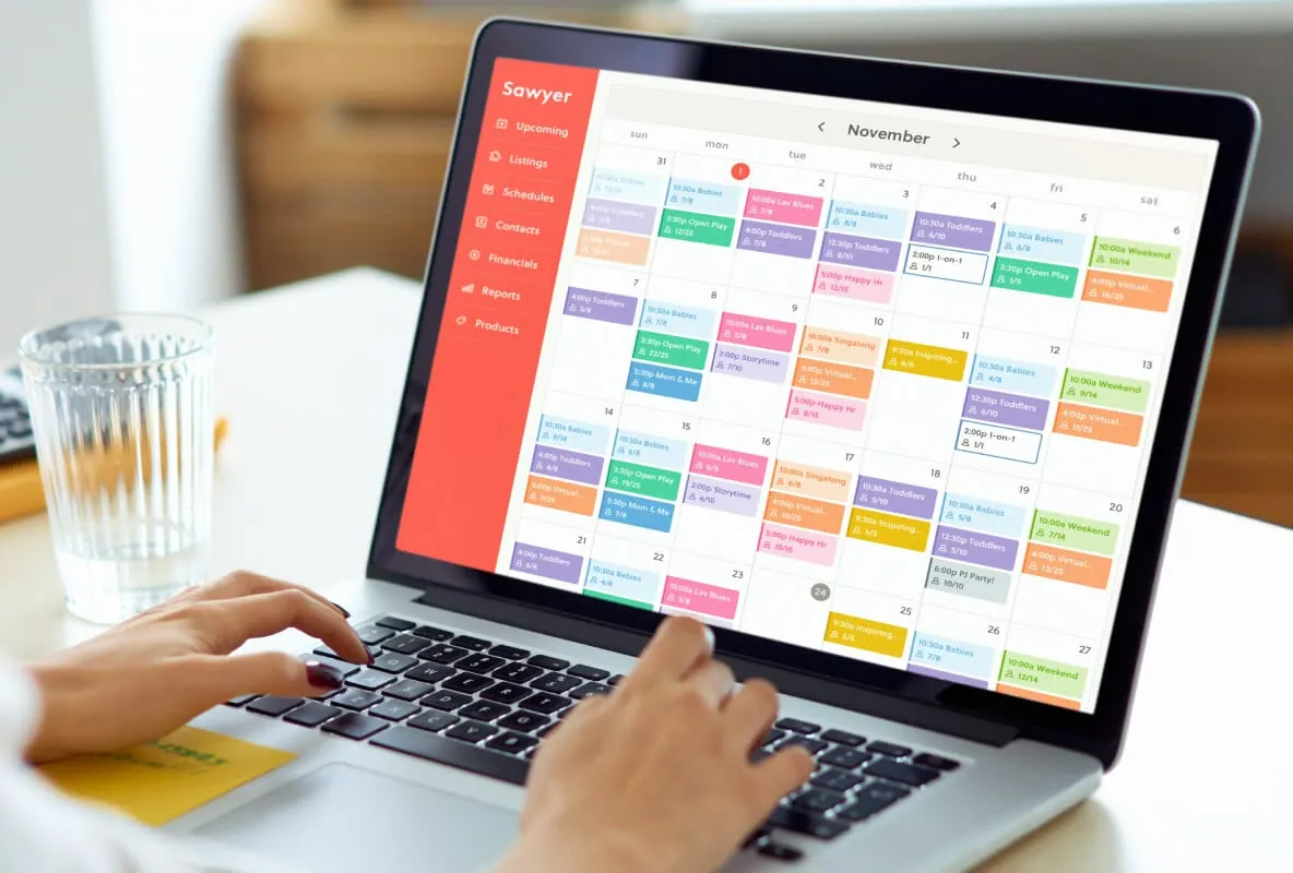 Close-up of a person typing on a laptop with a calendar and scheduling application open on screen